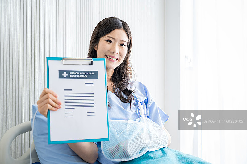 手臂骨折的亚洲女人拿医疗保险图片素材