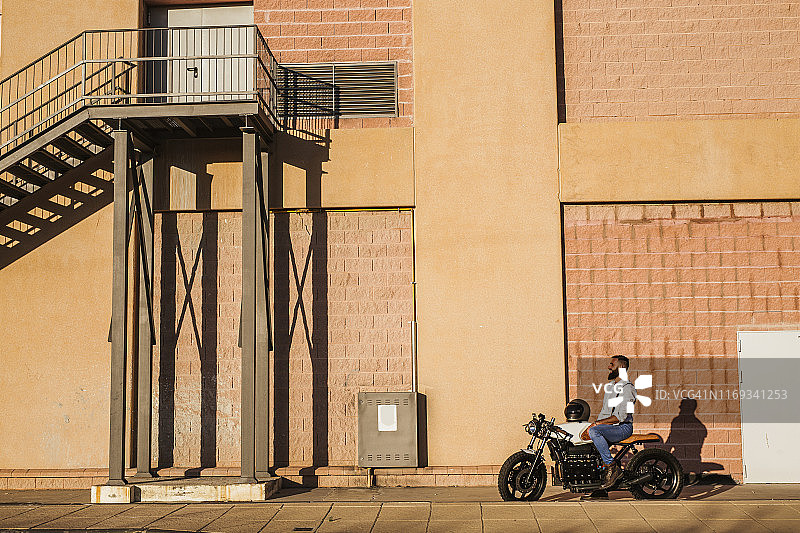 傍晚，坐在摩托车上欢笑的男人图片素材