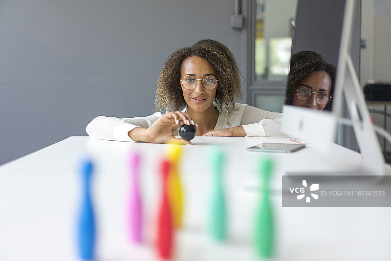 微笑的年轻自由职业者在桌子上玩迷你别针的肖像图片素材