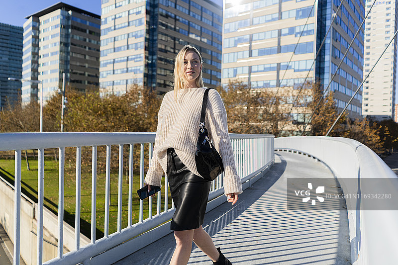 金发年轻女子在人行天桥上用手机的肖像图片素材