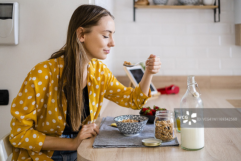 年轻女人在家中厨房享用早餐图片素材