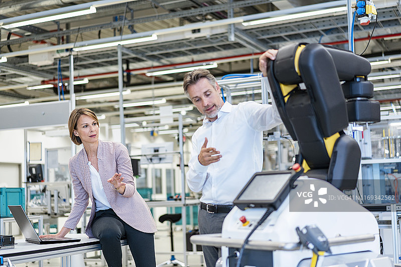 商人和女商人在现代工厂大厅交谈图片素材