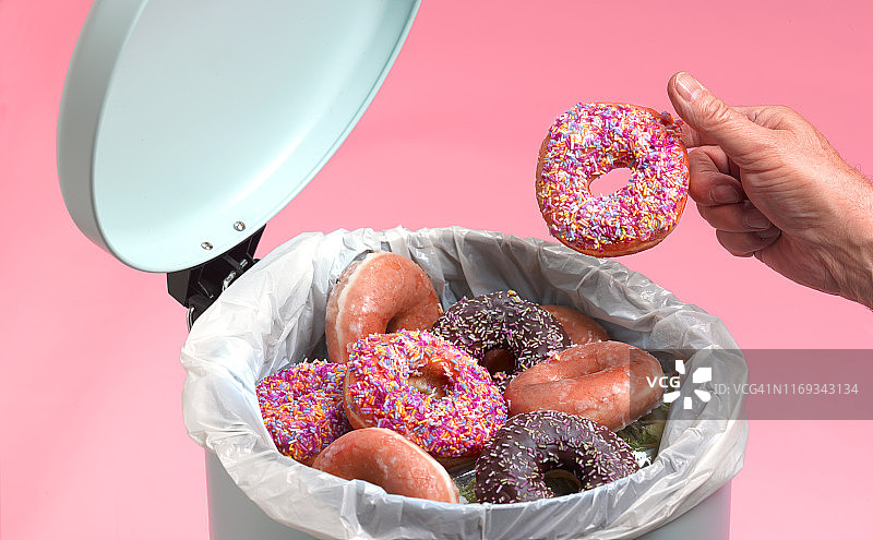 男人把甜甜圈扔进厨房垃圾桶图片素材