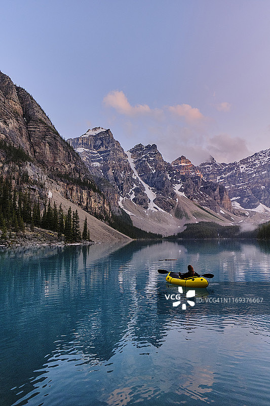 年轻女子在平静的湖面上划着充气筏图片素材