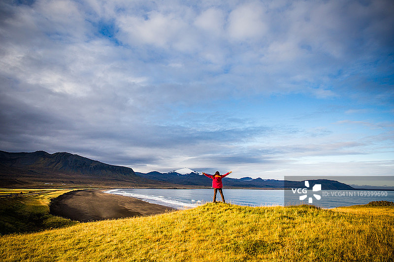 女子欣赏冰岛斯奈山半岛冰川前的黑沙滩图片素材
