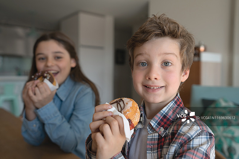 兄妹在家享用美味甜甜圈的特写图片素材