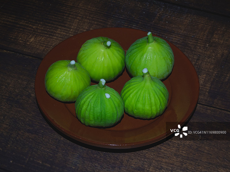 秋季水果：刚采摘的无花果，粘液在黏土盘的茎上图片素材