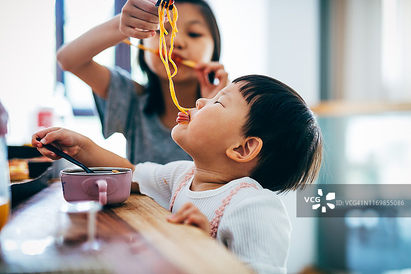亚洲女童和她的妹妹在家吃面条图片素材