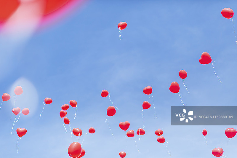 蓝色天空背景下的红色心形气球图片素材