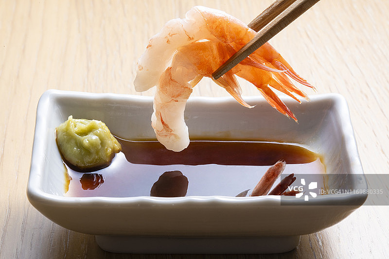 日式生鱼片：用筷子夹甜虾，加入酱油图片素材
