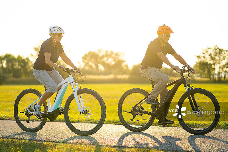 快乐的退休人员在阳光下骑自行车图片素材