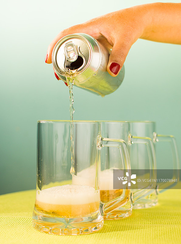 手将啤酒罐倒入啤酒壶中图片素材