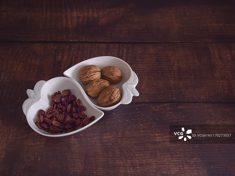 秋季水果：心形瓷碗中盛放的坚果和葡萄干图片素材