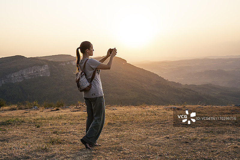 回归自然：阳光明媚的日子里，独自旅行的快乐年轻女游客在山区享受户外活动。图片素材