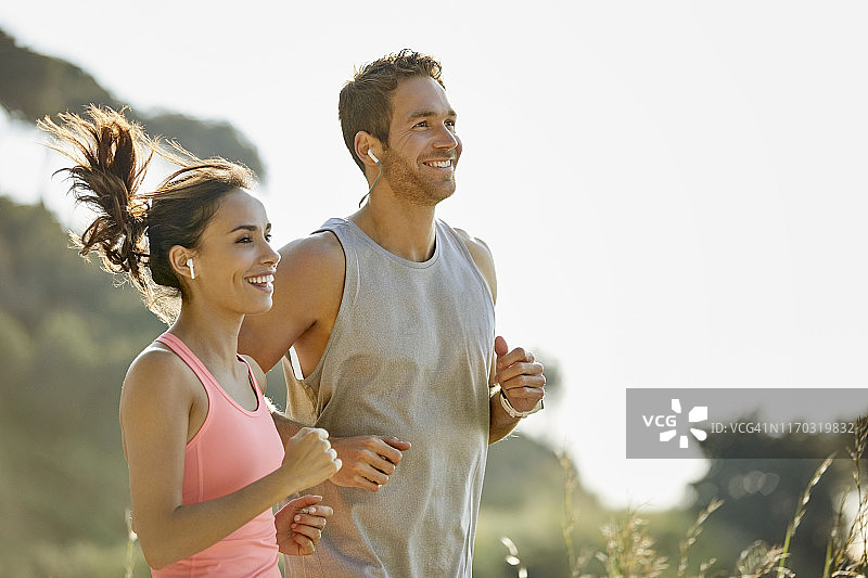 幸福情侣戴着耳机在公园慢跑图片素材