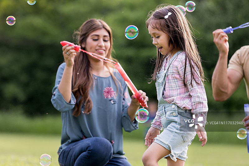 幸福的三口之家在公园里玩泡泡图片素材