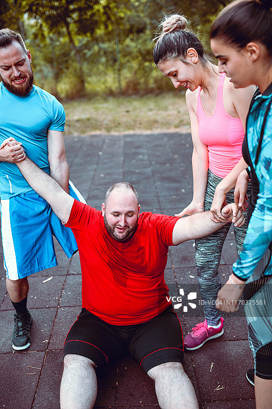 朋友们在艰苦训练后拉起超重的男人图片素材
