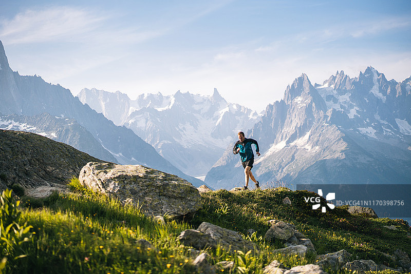 清晨在山间草甸奔跑的越野跑者图片素材