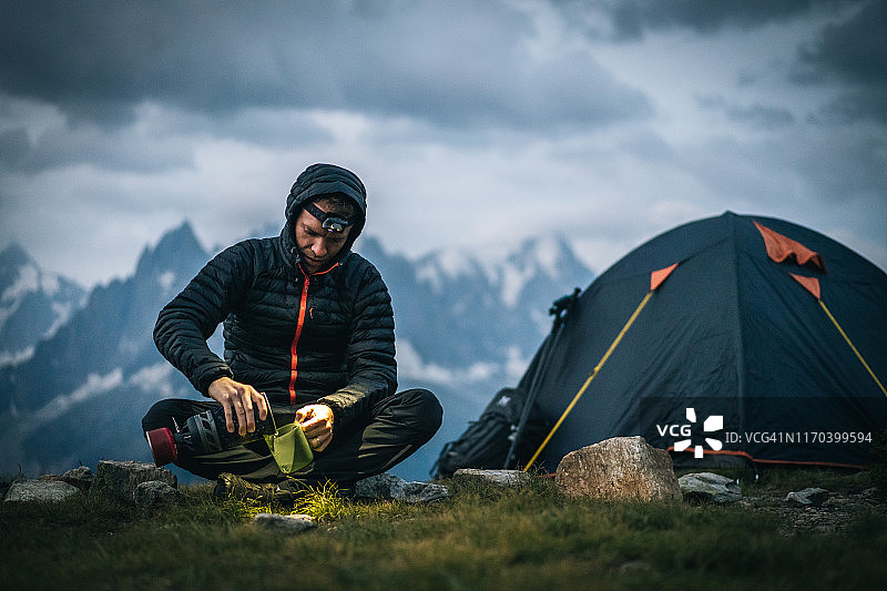徒步旅行者在高山营地用头灯准备热饮图片素材