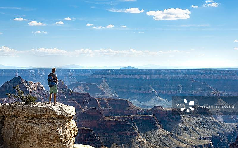 美国大峡谷北缘明亮天使观景点峡谷风光和岩石上的男子图片素材