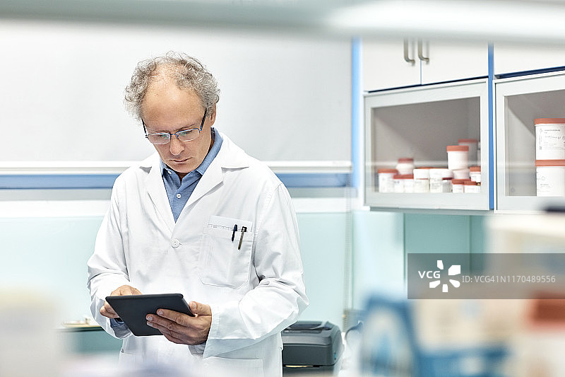 年长的男性顺势疗法医师在医院使用平板电脑图片素材