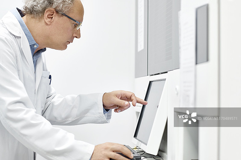 男科学家在实验室指向电脑显示器图片素材