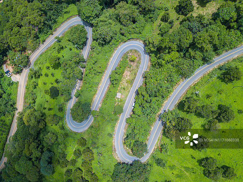 泰国清莱府高地山区绿色森林中的弯曲道路航拍图片素材