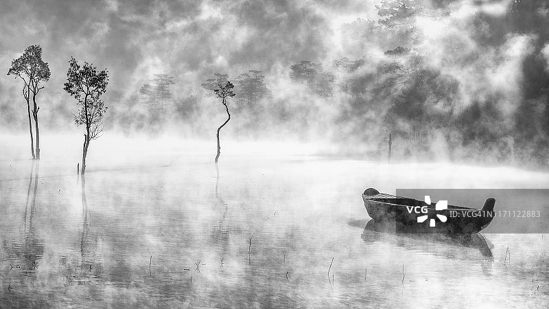 日出时分，迷雾笼罩的湖面上孤独的渔船图片素材