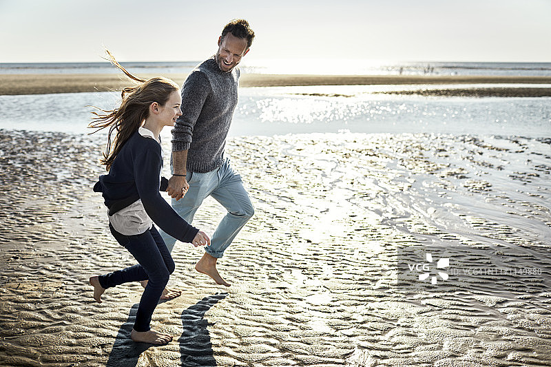快乐的父女在海滩上奔跑图片素材