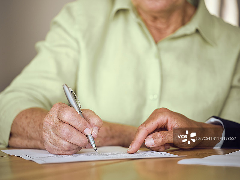 年长的女人在家中签署文件图片素材