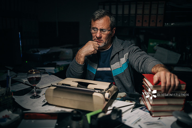 年长的作家在夜晚安静地工作图片素材