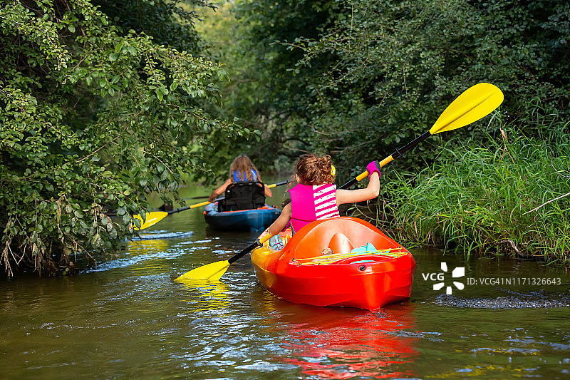 两个年轻的女孩在狭窄的溪流中划皮划艇图片素材