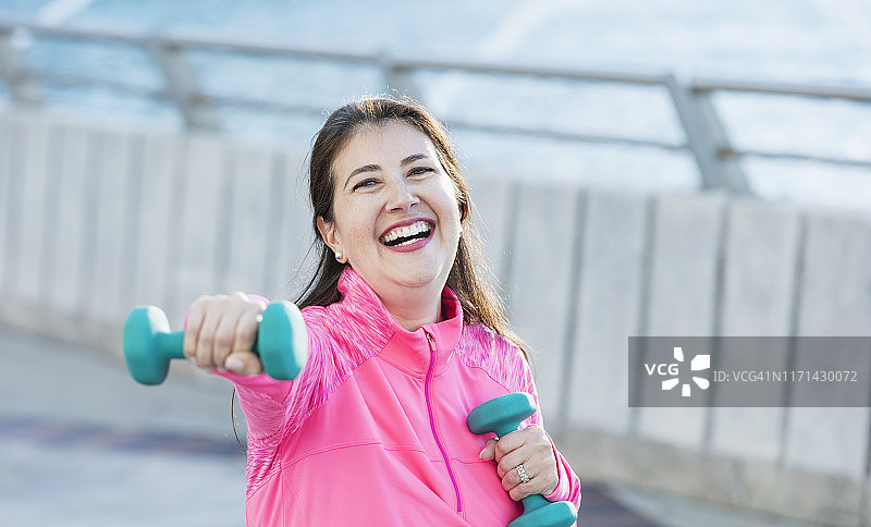 用手持重物锻炼的年长的西班牙裔女人图片素材