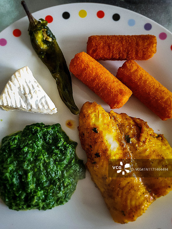包含炸鱼条、菠菜、辣椒、卡门培尔奶酪和炸丸子的餐点图片素材