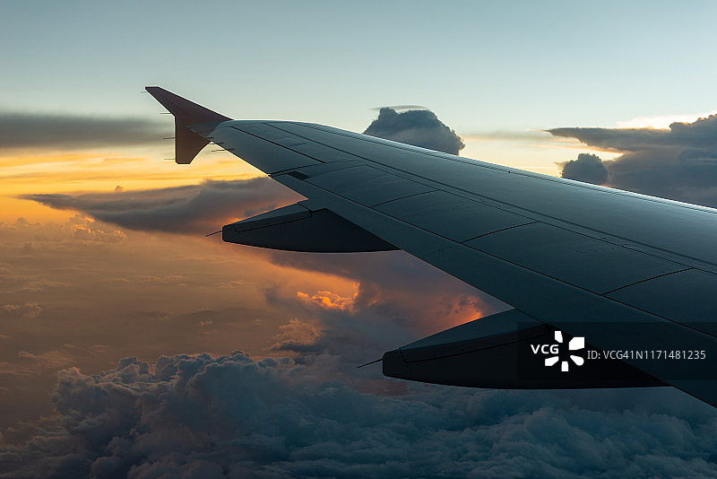 飞机舷窗外日落时分壮丽而美丽的云景，可见飞机机翼图片素材