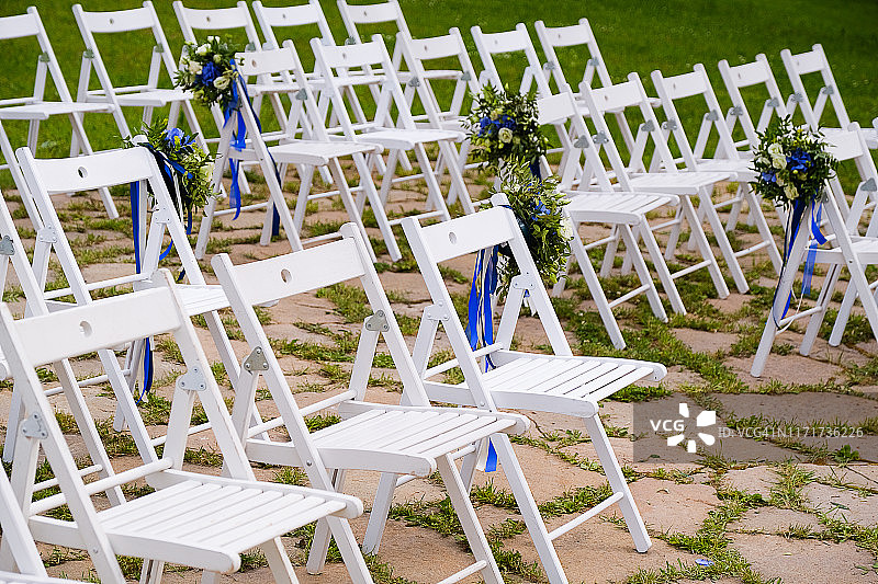 户外用鲜花花束和明亮缎带装饰的白色木椅，婚礼装饰图片素材