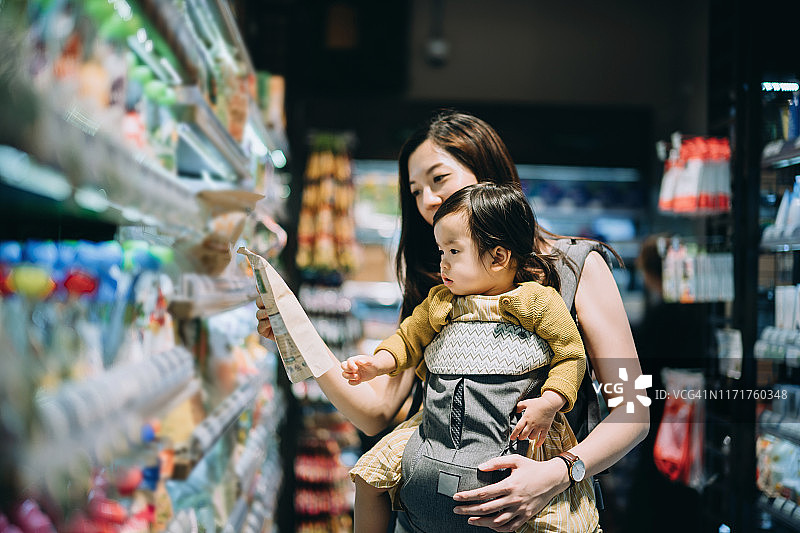 年轻的亚洲母亲和女儿在超市购买食品，并为婴儿选择有机食品图片素材