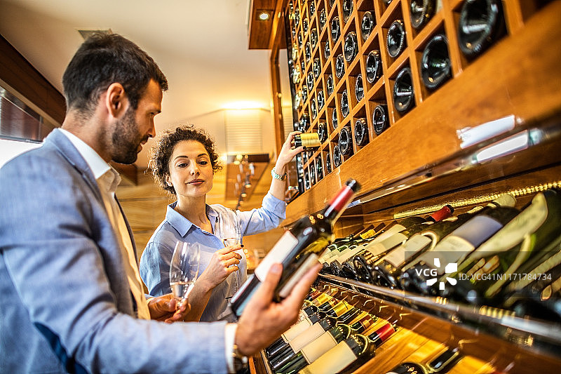 情侣在豪华餐厅的酒架旁选酒图片素材