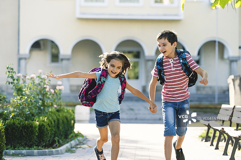 返校季：快乐的孩子们背着书包奔跑图片素材