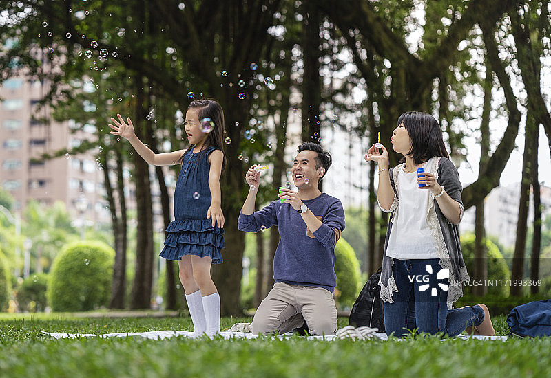父母看着在公园里玩耍的女儿图片素材