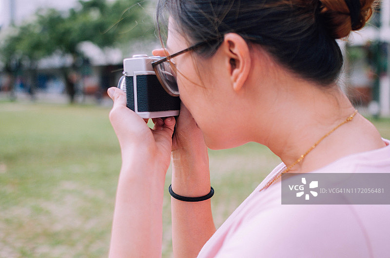 在户外使用老式相机的年轻女人图片素材