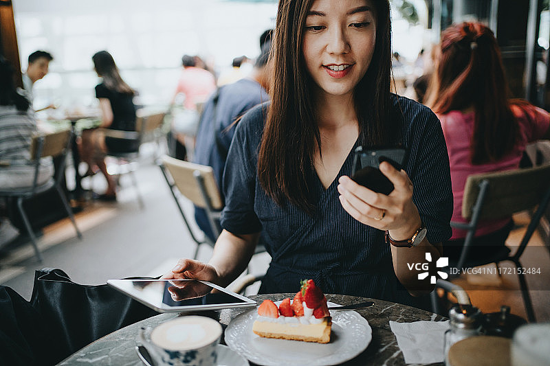 忙碌的年轻女人在户外咖啡馆使用手机和平板图片素材