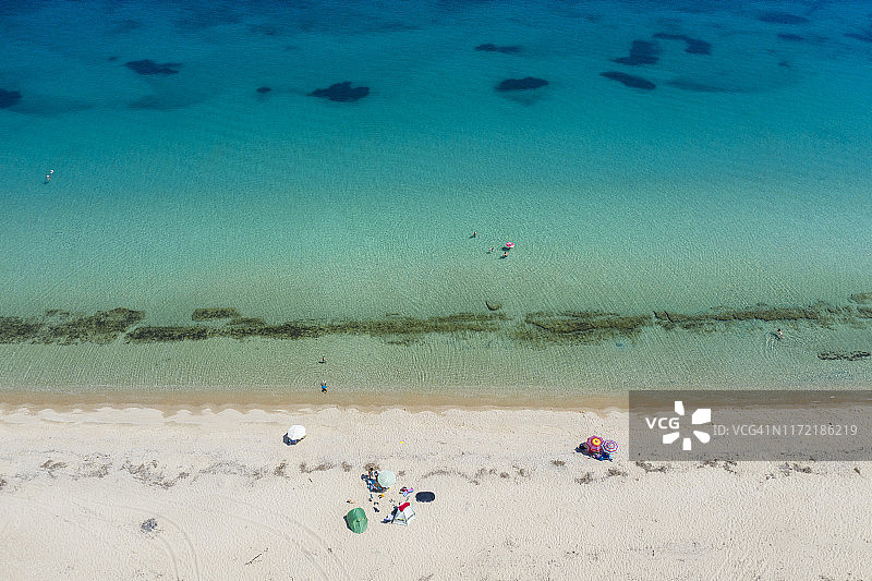 阳光明媚，海湾中游泳的人群和沙滩上阳伞的航拍景色图片素材