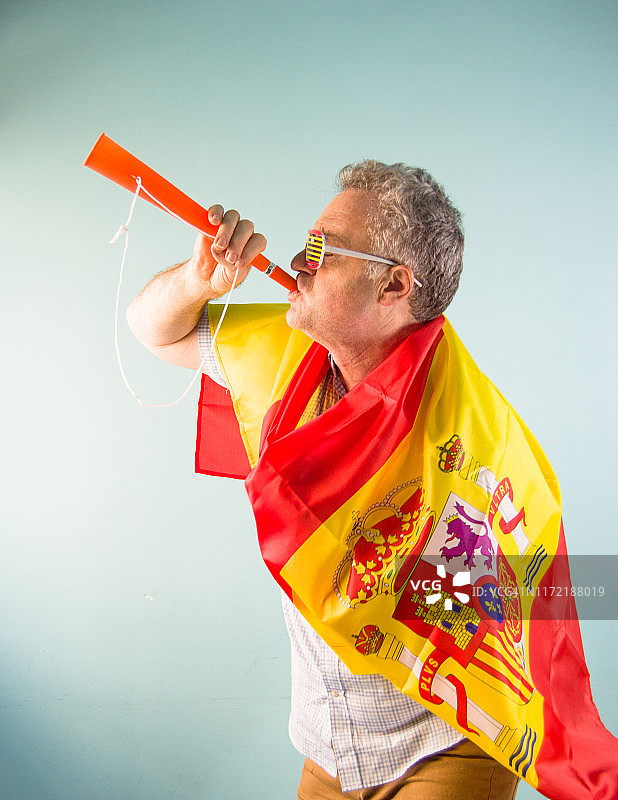 西班牙球迷在家吹奏呜呜祖啦，为西班牙国家足球队欢呼图片素材