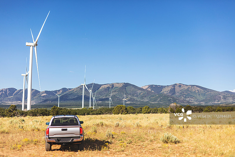 停在美国西部公路上的皮卡，犹他州蒙蒂塞洛附近沙漠、山脉和风力涡轮机图片素材