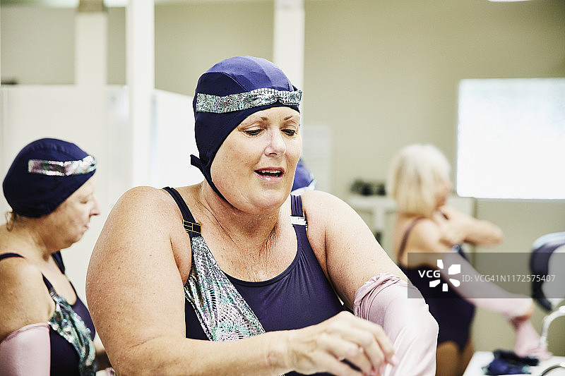 年长的女子花样游泳运动员在更衣室与队友一起准备表演图片素材