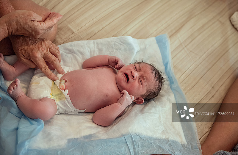 居家分娩：新生儿啼哭，助产士检查脐带夹图片素材