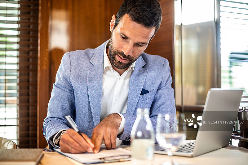 小型企业主坐在餐厅里在剪贴板上写东西图片素材