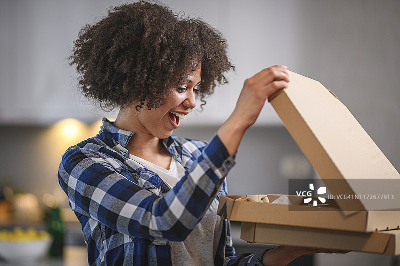 看着外卖披萨的兴奋混血年轻女人图片素材