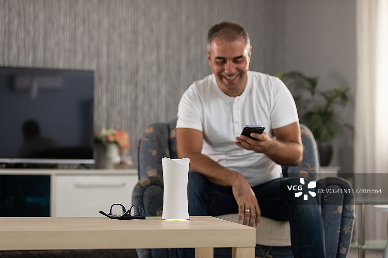 男人在家使用智能手机和智能家居设备图片素材